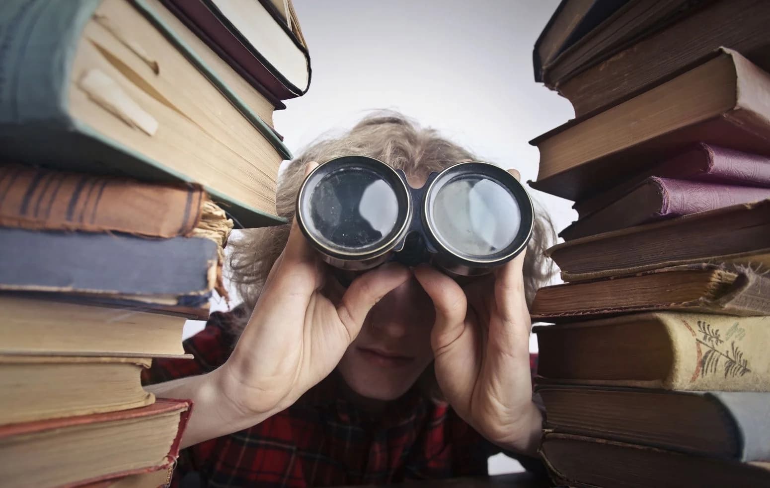 Ein Fernglas zwischen Büchern: ein Audit liest die Seiten und schaut dann, was die Suchmaschinen sehen